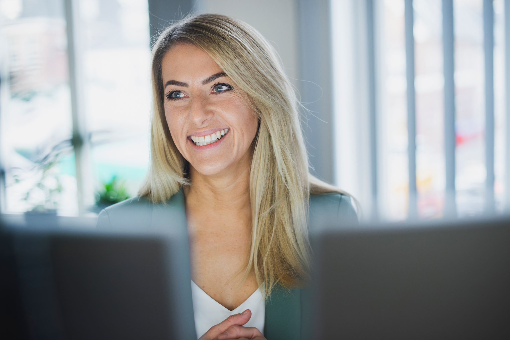 Mitarbeiterin arbeitet lächelnd am Laptop, im Büro von medcareer